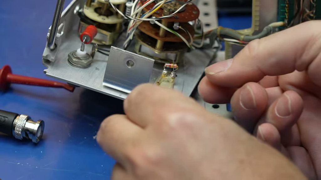 Hands working inside an HP 5221B Nixie frequency counter during CuriousMarc’s restoration